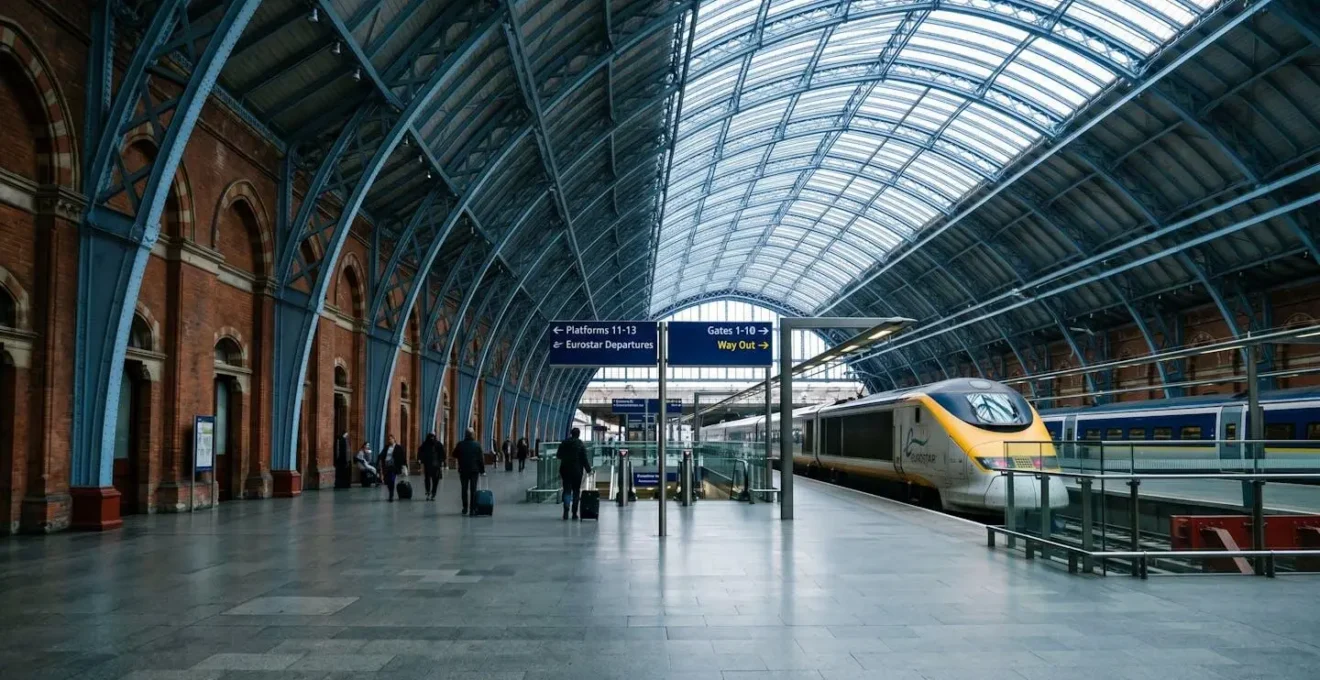 Gare de St Pancras International à Londres avec un train Eurostar stationné sous la verrière victorienne, voyageurs se dirigeant vers les quais